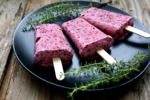 Berry popsicles on plate with herbs