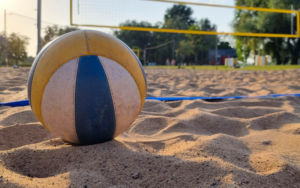 Blue, yellow and white beach volleyball sitting in the sand