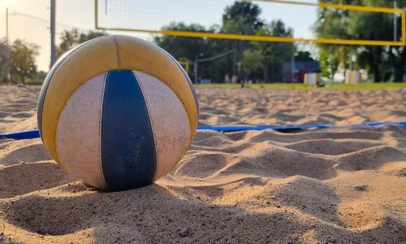 Blue, yellow and white beach volleyball sitting in the sand