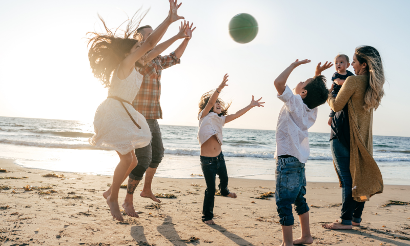 Family of six playing with a ball on the beach