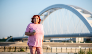 Woman in pink walking outside listening to music