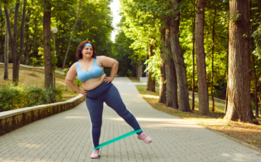 Young woman using resistance bands in the park while exercising during summer.