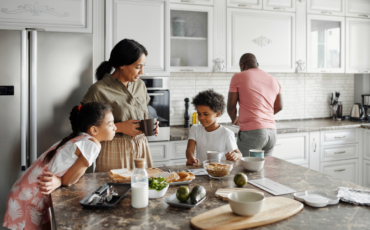 Parents and two kids spending time together in the kitchen before school in the morning