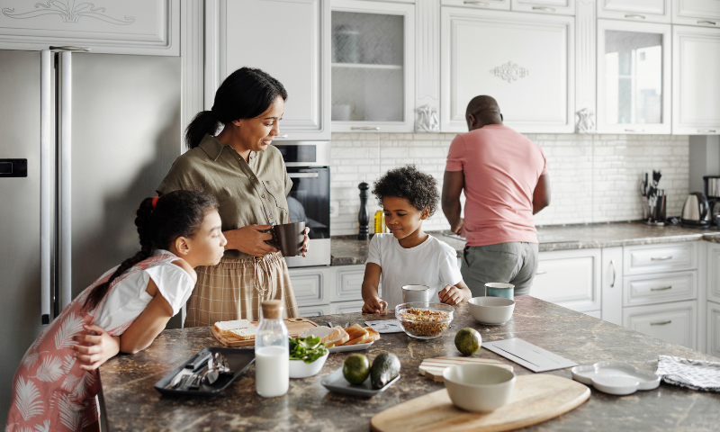 Parents and two kids spending time together in the kitchen before school in the morning