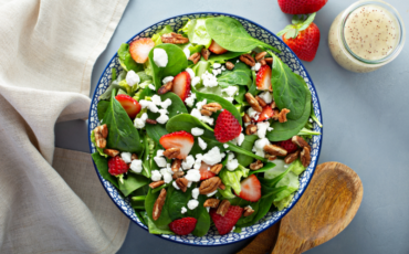 Bowl of strawberry spinach salad with nuts and goat cheese