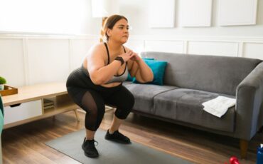 Image of young woman doing squats in her living room