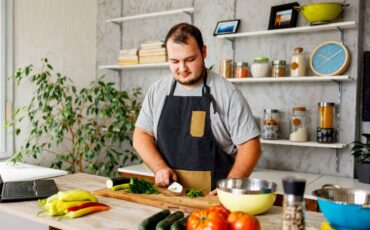 Young adult man cooking healthy food in kitchen