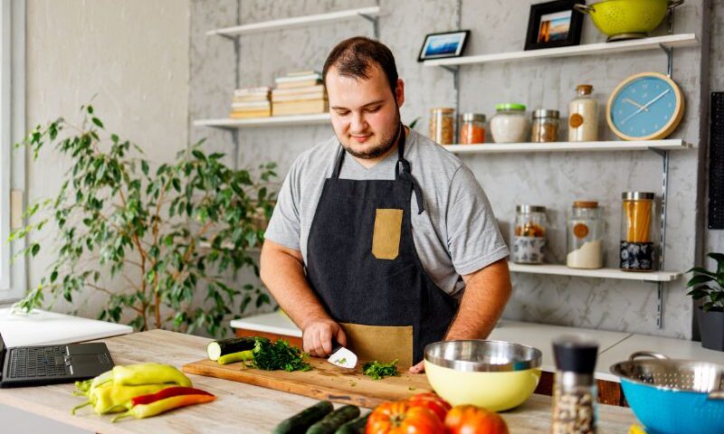 Young adult man cooking healthy food in kitchen