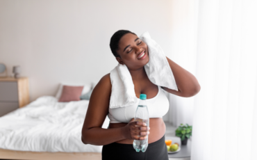 Young black woman cools off after exercise with a bottle of water and a sweat towel