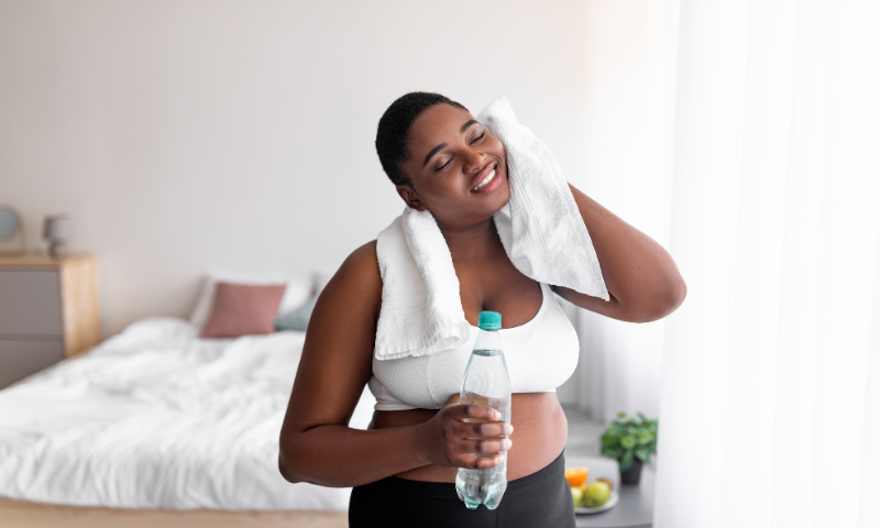 Young black woman cools off after exercise with a bottle of water and a sweat towel