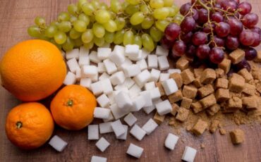 Image: Oranges and grapes on the same table as white and brown sugar cubes