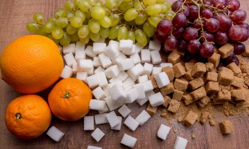 Image: Oranges and grapes on the same table as white and brown sugar cubes