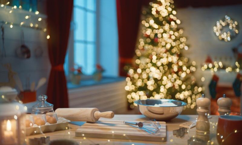 Photo of baking tools and ingredients for baking cookies, in front of a holiday tree