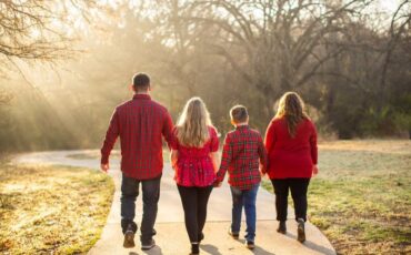 Four people dressed in holiday red go on a walk outside