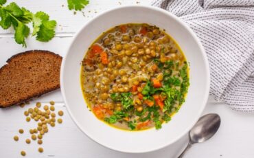 Bowl of lentil vegetable soup next to a slice of bread